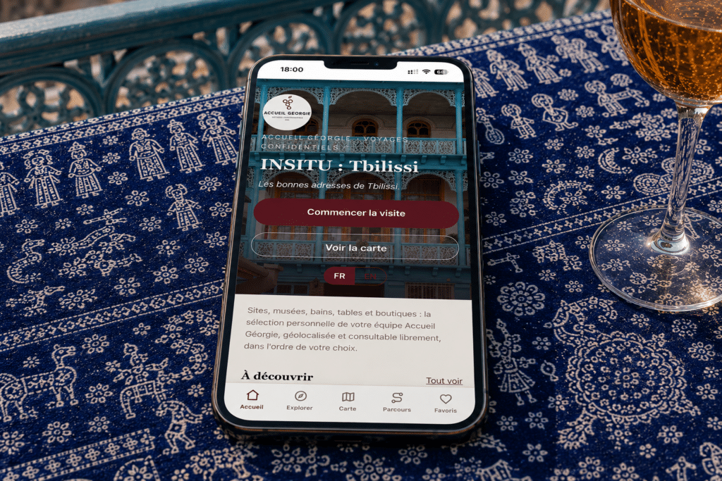 INSITU Tbilissi, le guide interactif privé d'Accueil Géorgie, sur un téléphone posé sur une nappe lurji supra